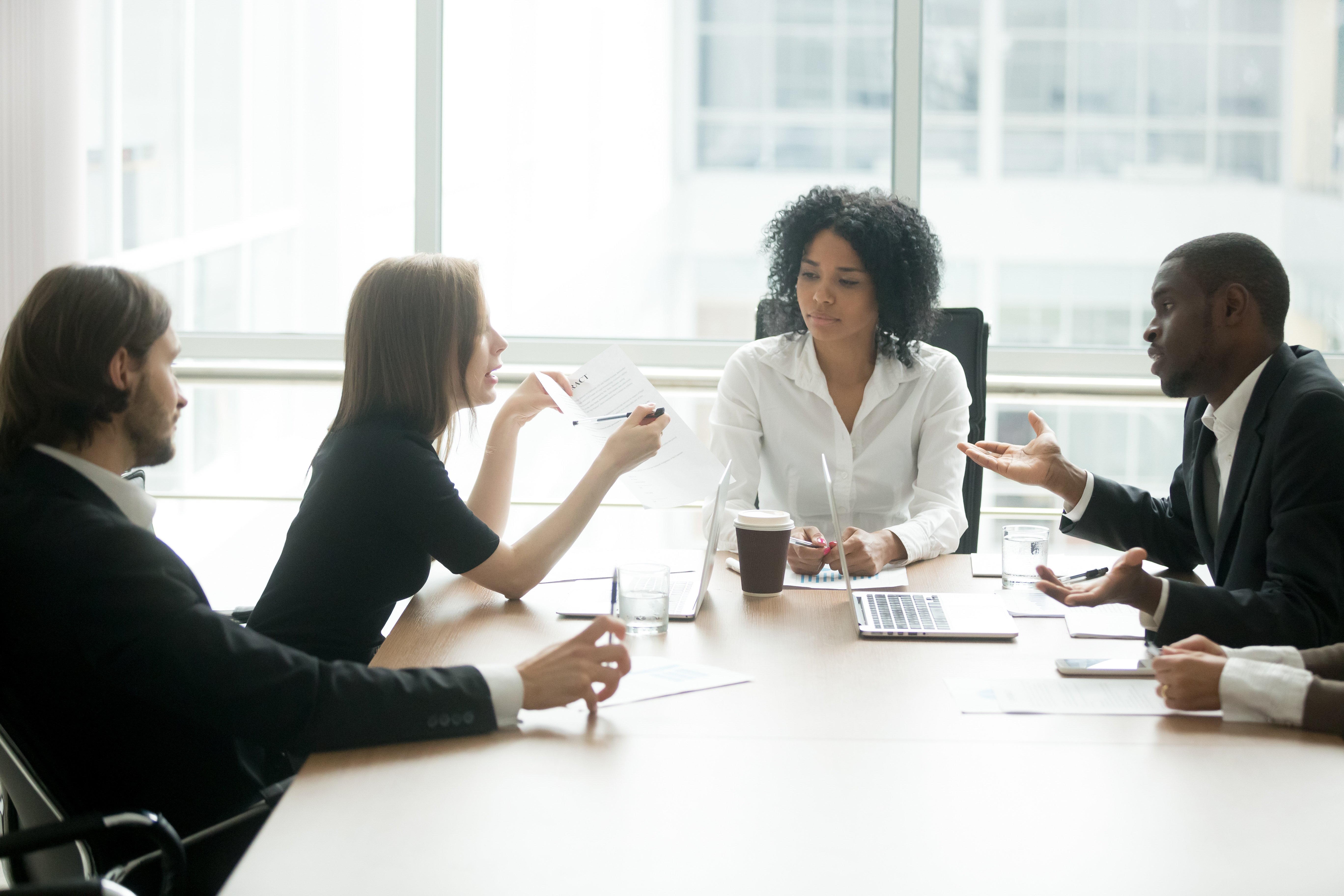 two parties negotiate the terms of a contract at a table in an office