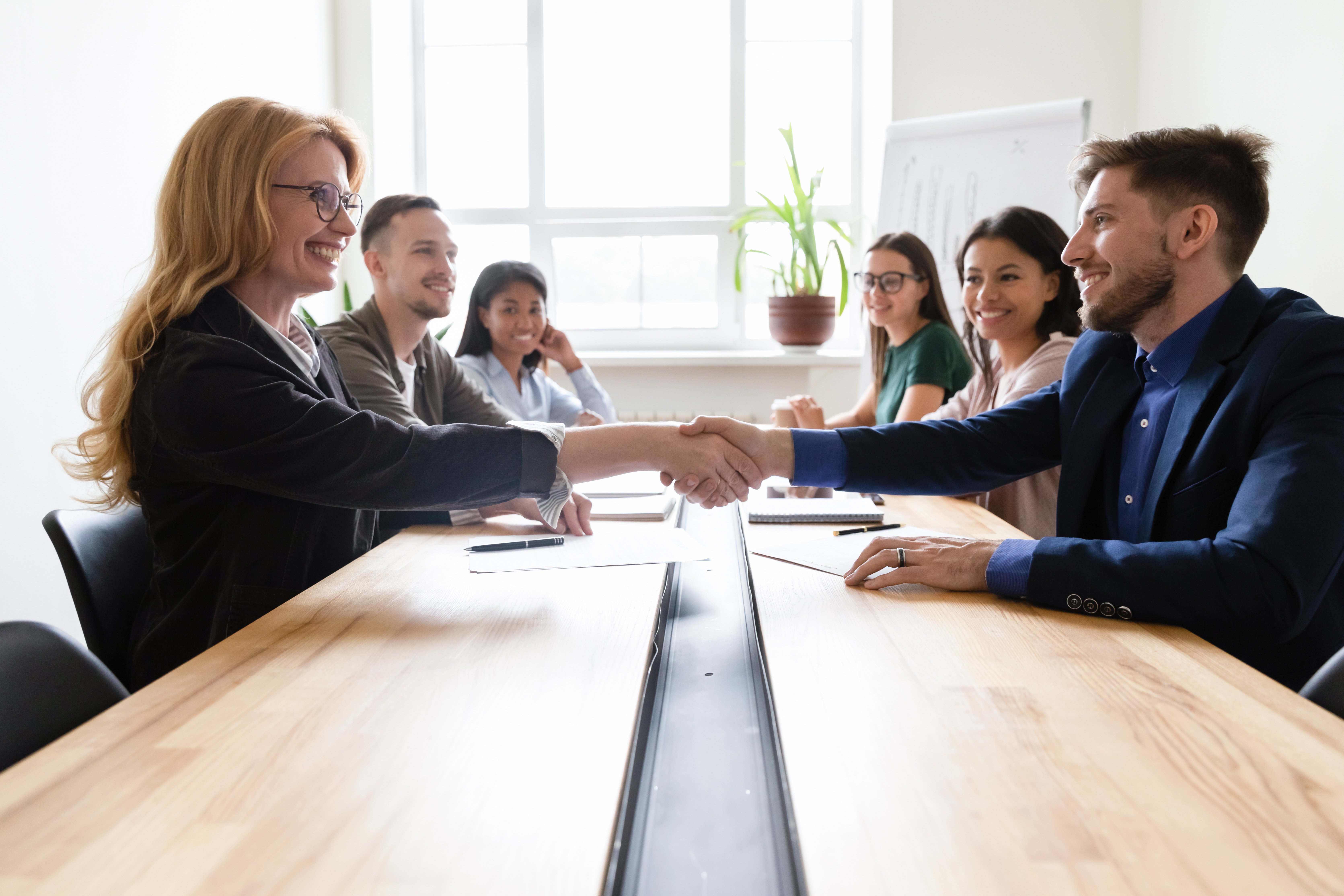 woman shaking hands with man after coming to an agreement during negotiations