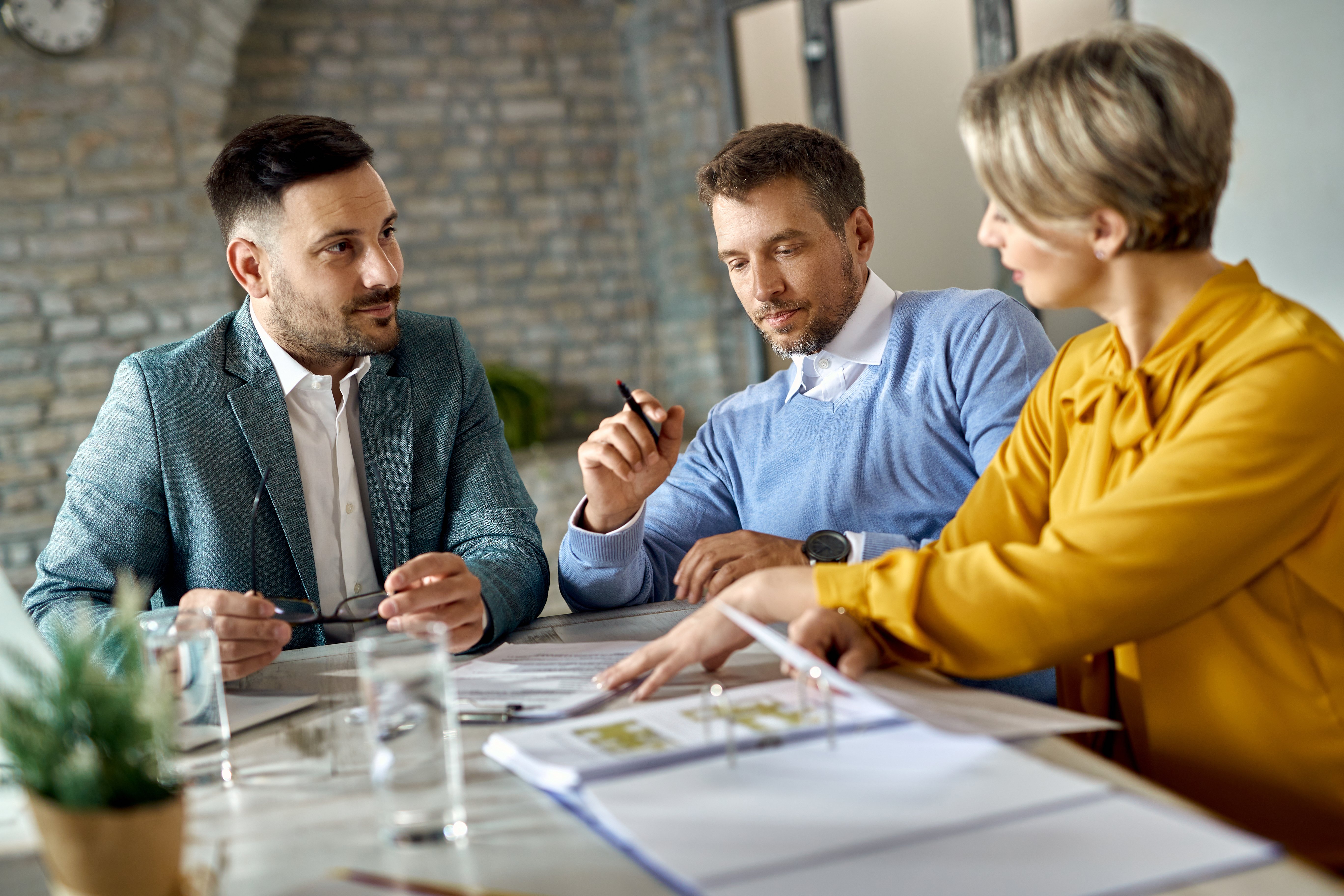 man negotiating contract with a man and woman in an office