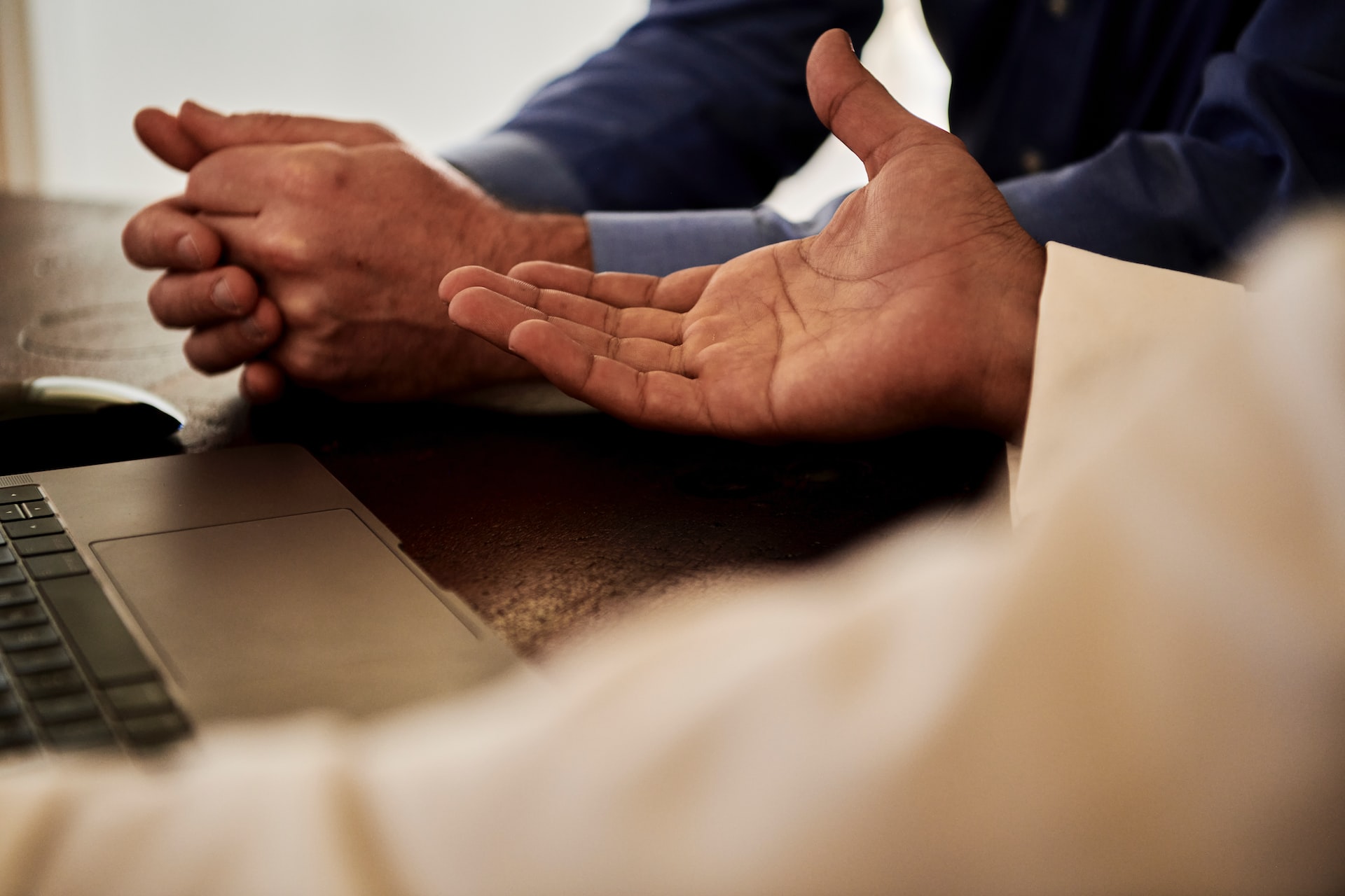 A close-up of two sets of hands. One person’s hand is outstretched, looking to make a deal. 